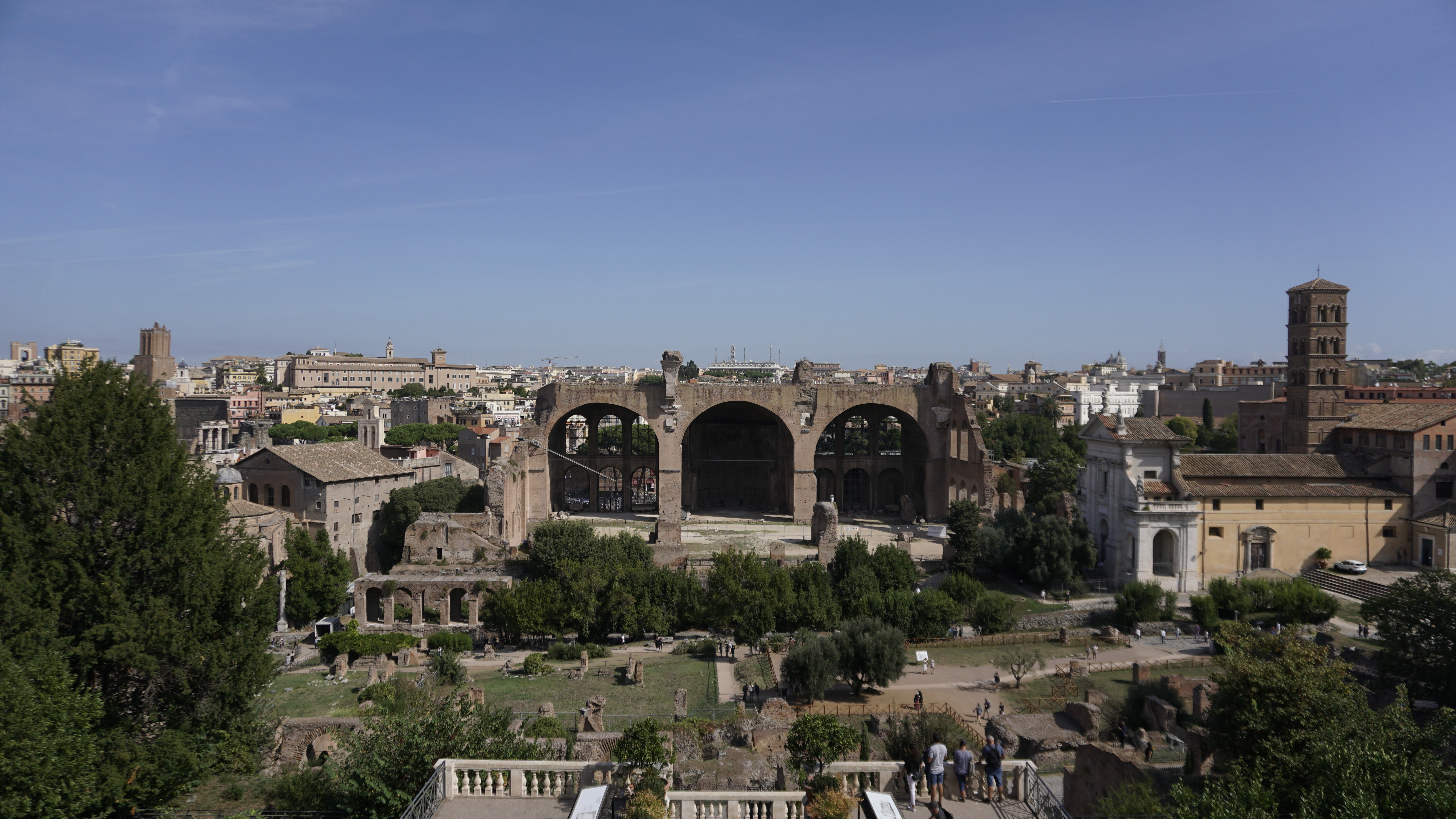 Ancient Roman arches and ruins overlook a city panorama.