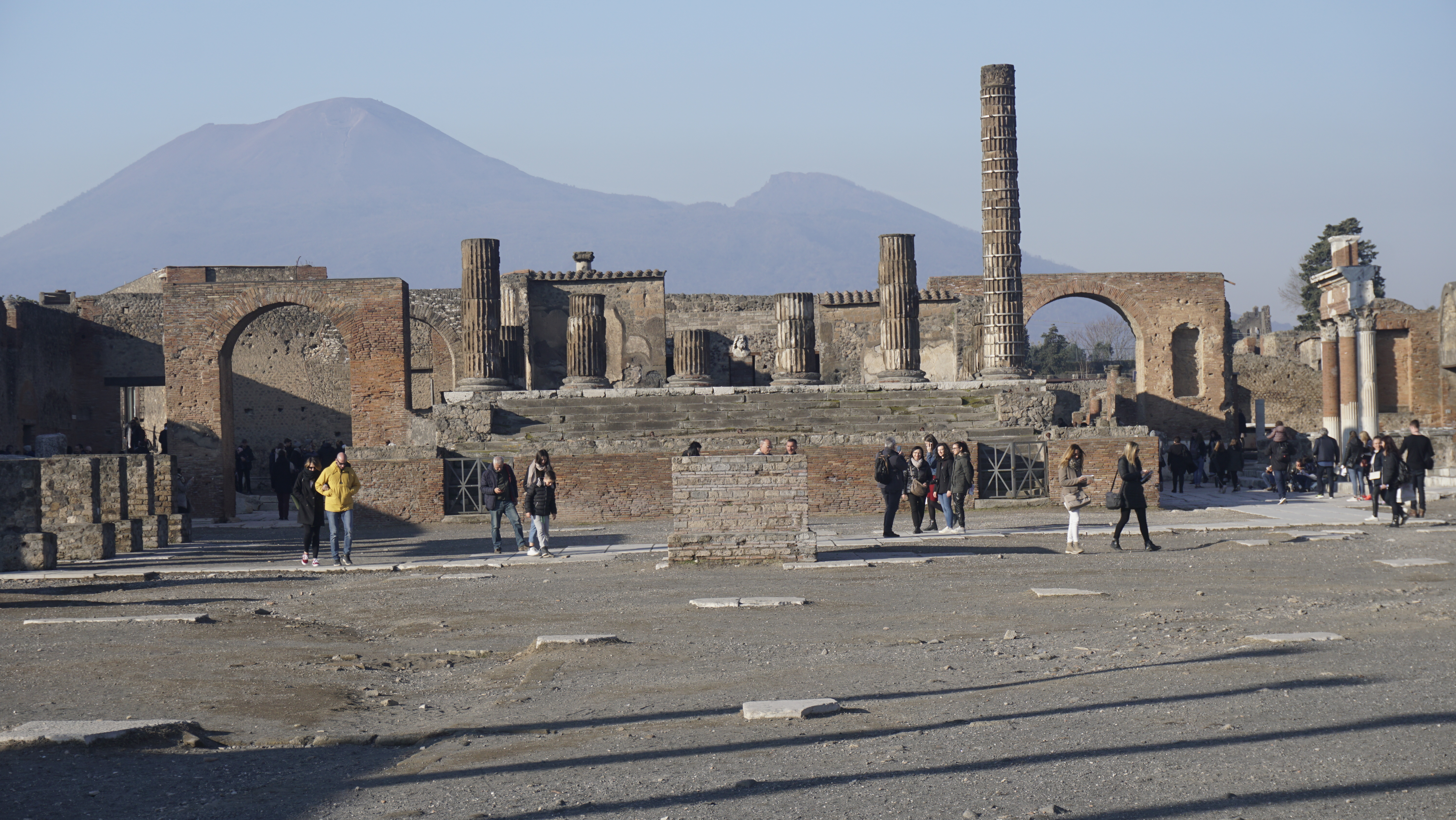 Ancient columns and brick arches with a hazy mountain behind.