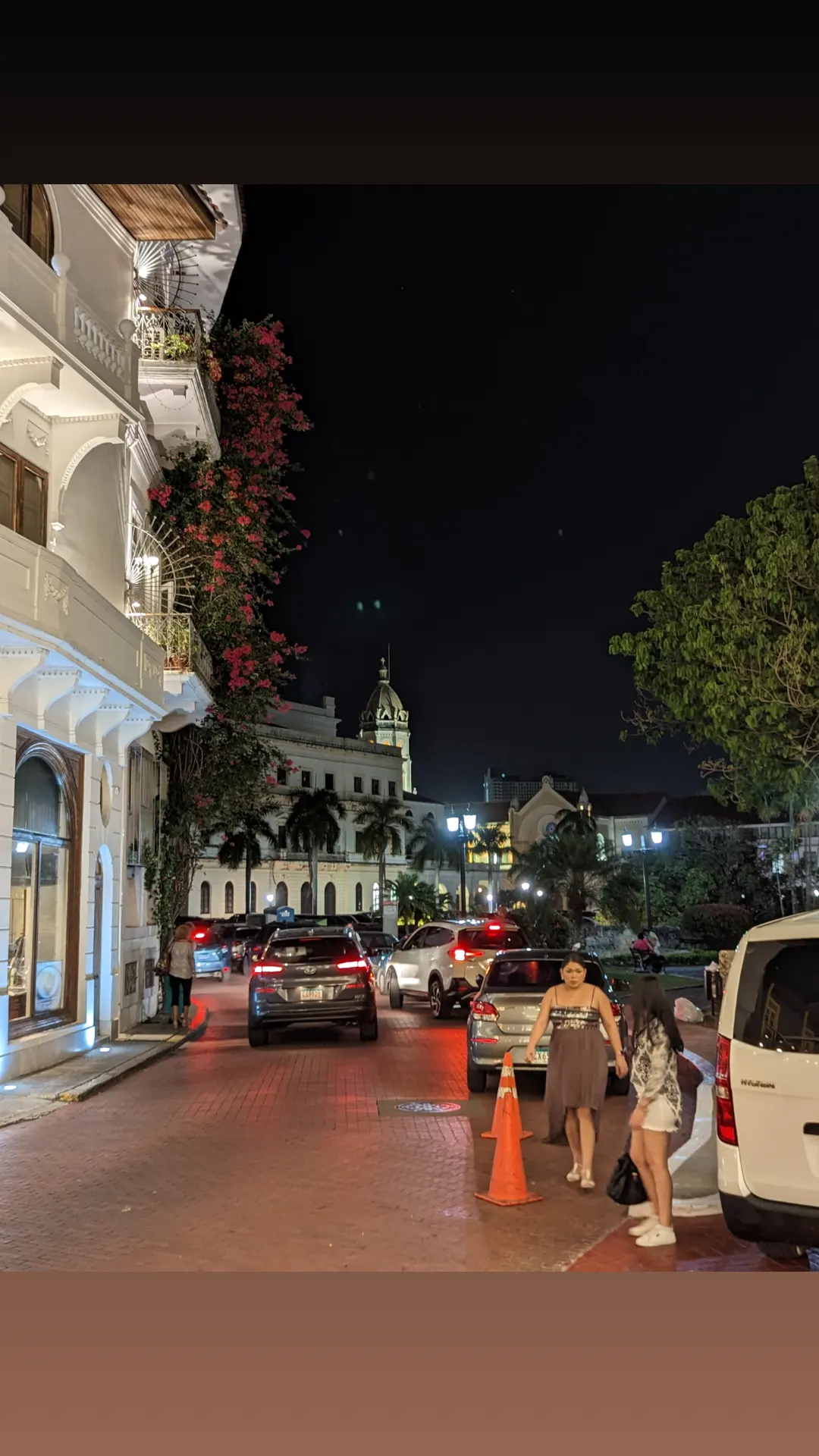 People fill a warmly lit old-town street at night.