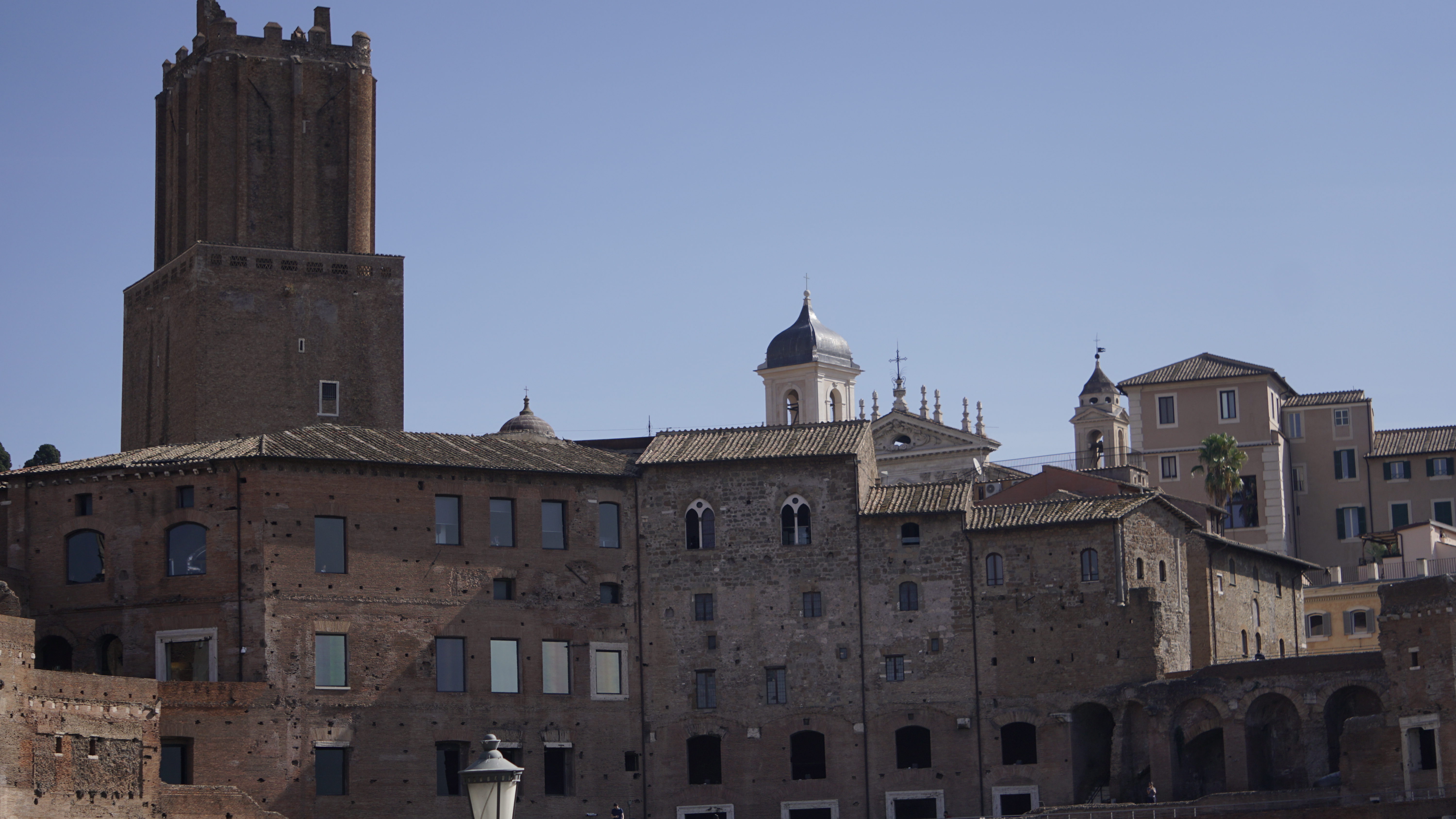 A brick tower rises above historic stone buildings.